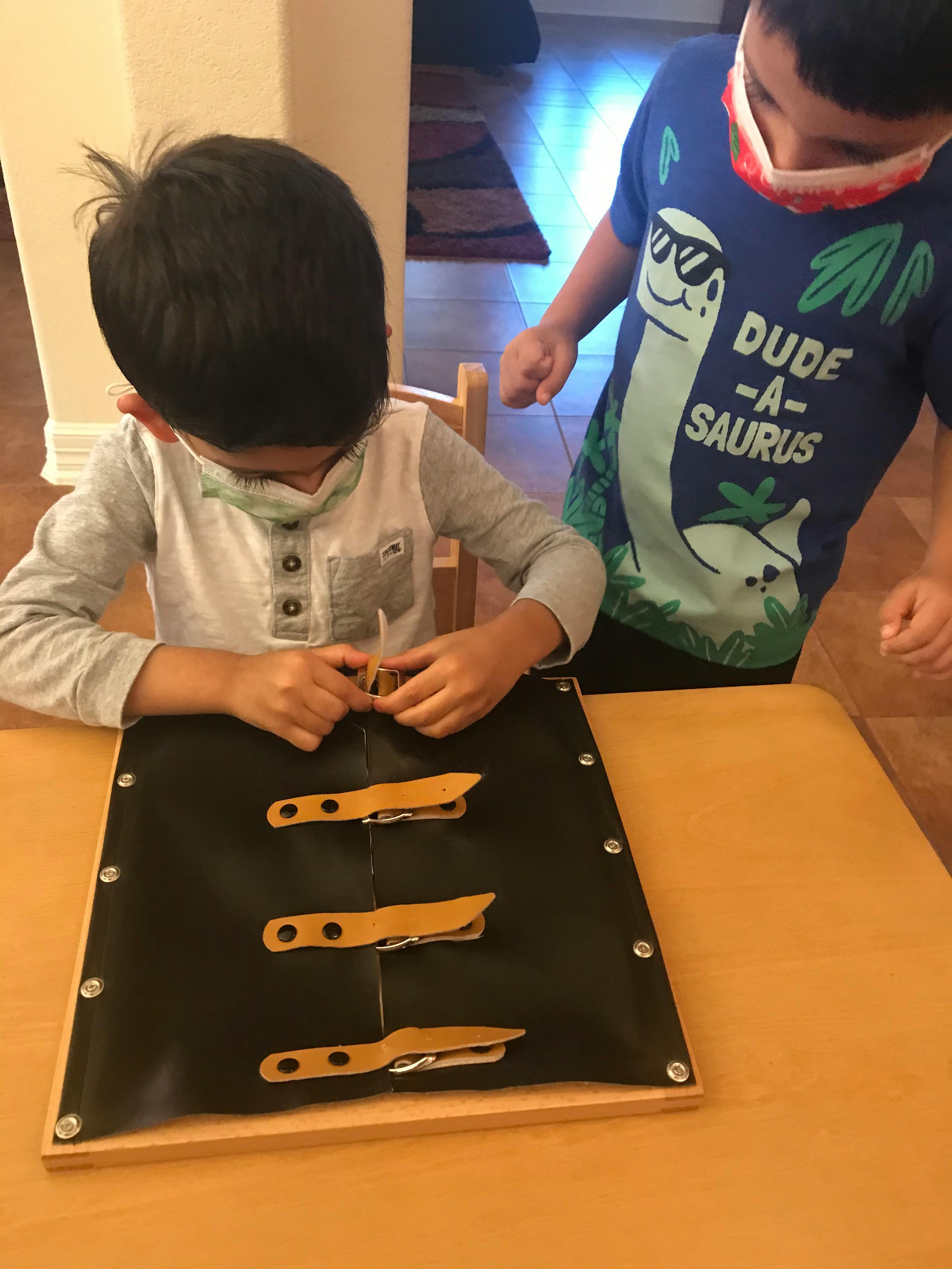 Child manipulating a zipper board while another child watches