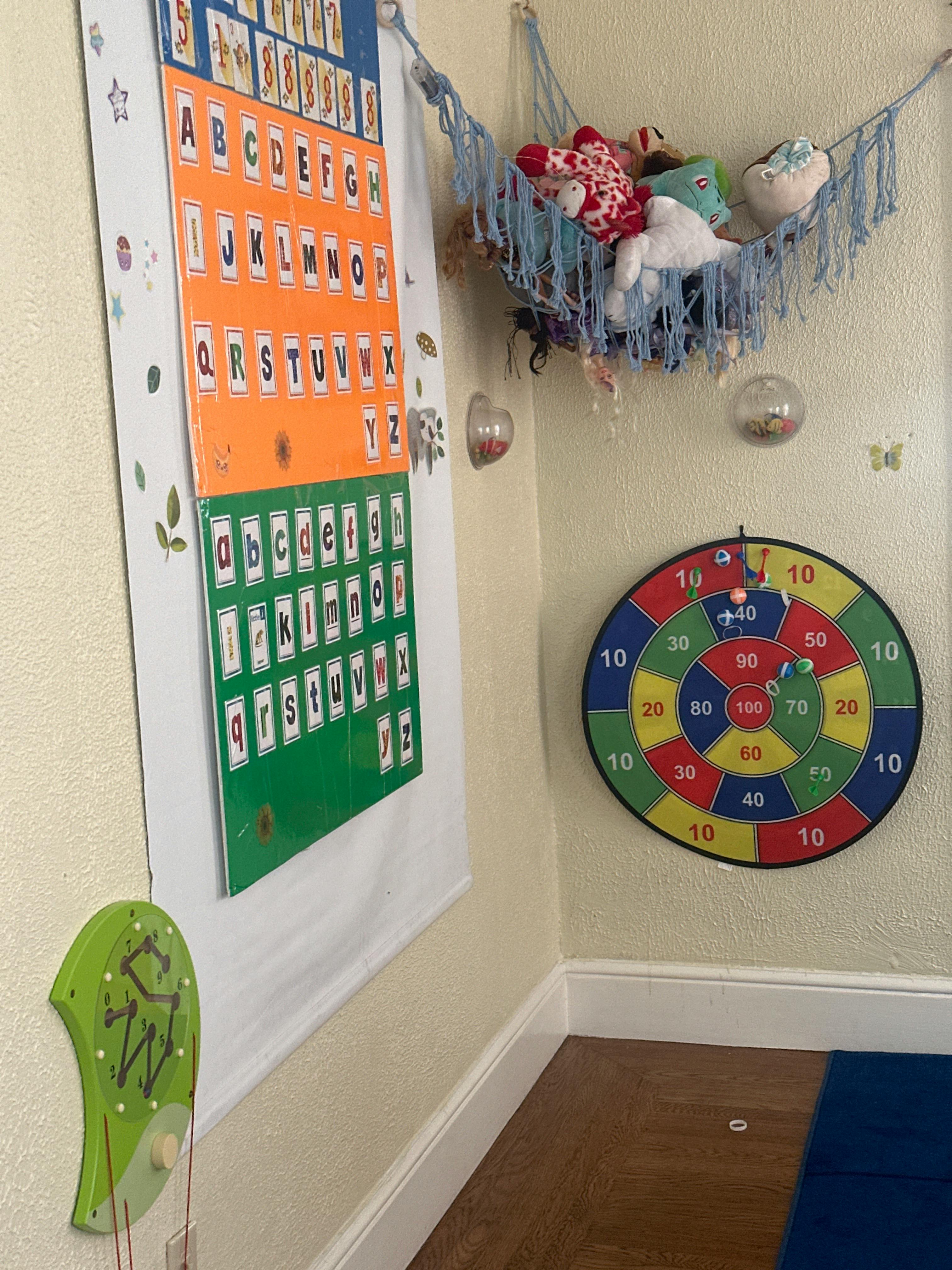 Alphabet chart, stuffed animal hammock, and dartboard on a wall