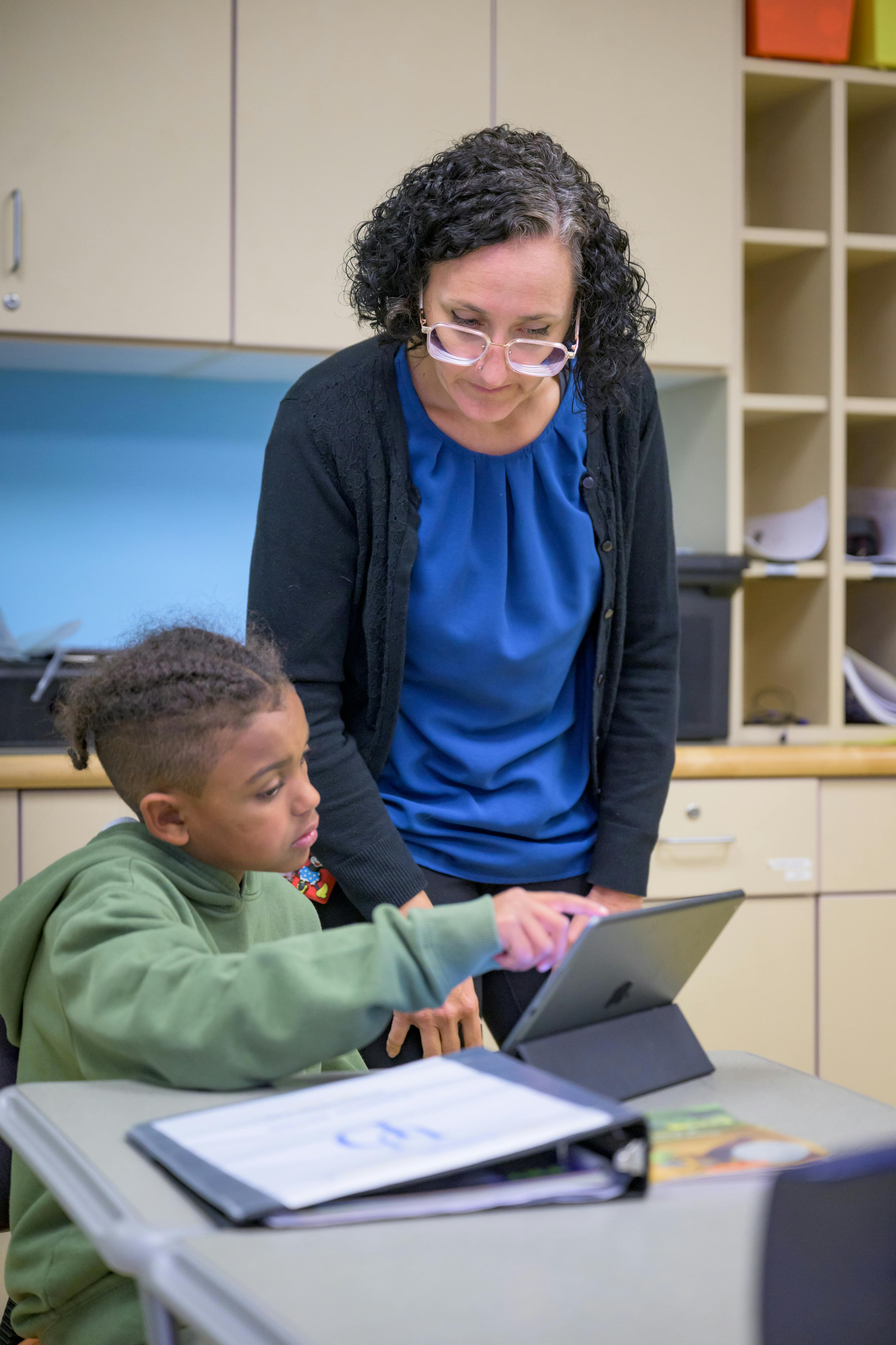 Person and child looking at a tablet in a classroom