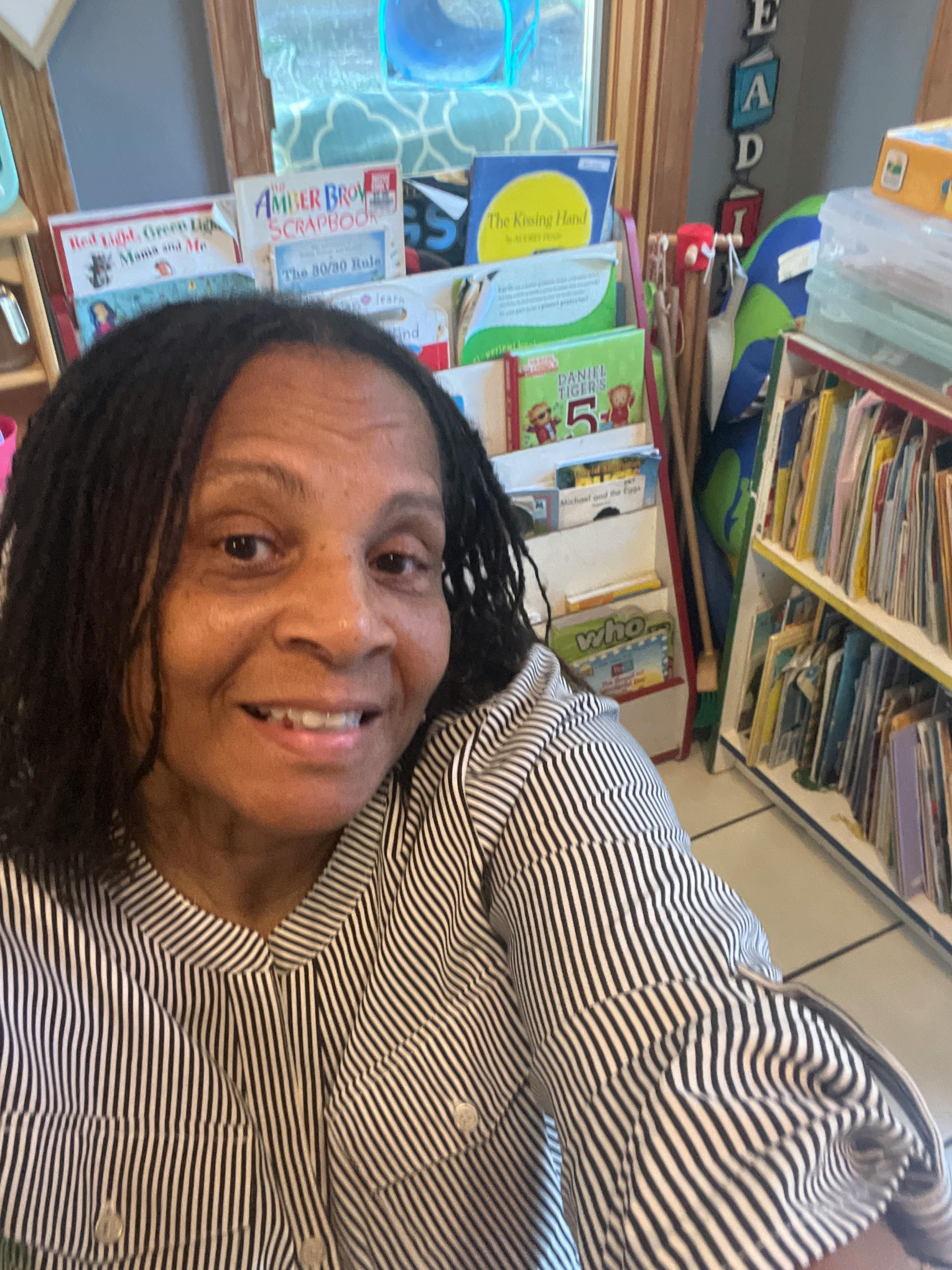 Person with dreadlocks wearing a striped shirt in a classroom