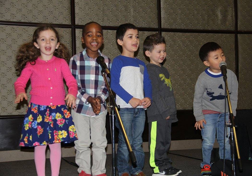 Five children standing at microphones