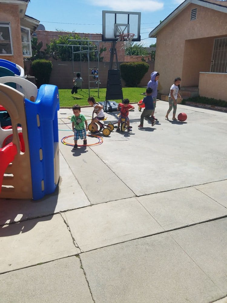 Children playing outdoors on a paved area with a basketball hoop