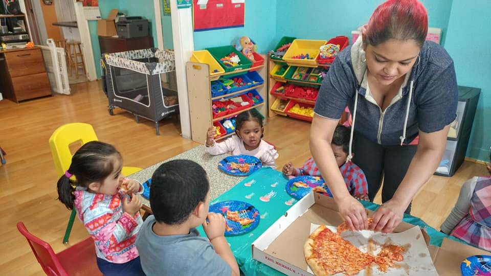 Person serving pizza to children at a table