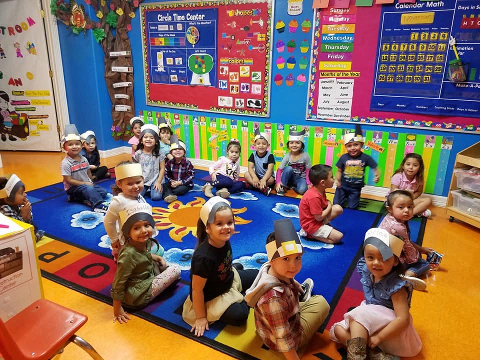Group of children sitting on a colorful rug in a classroom