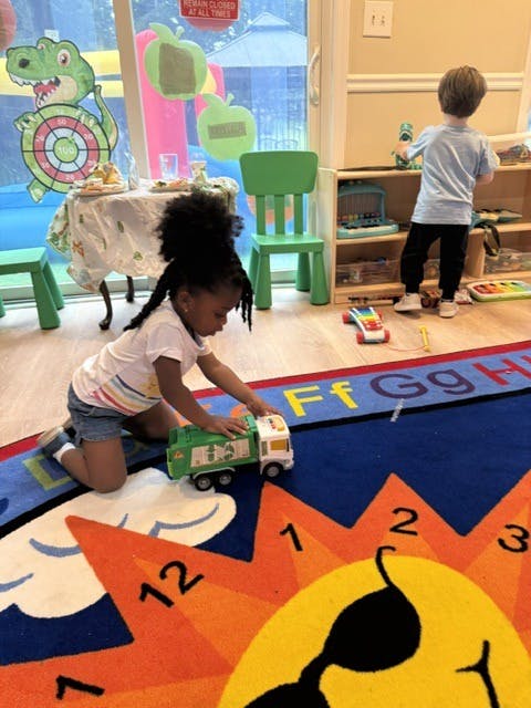 Child playing with a toy truck on a colorful rug in a playroom