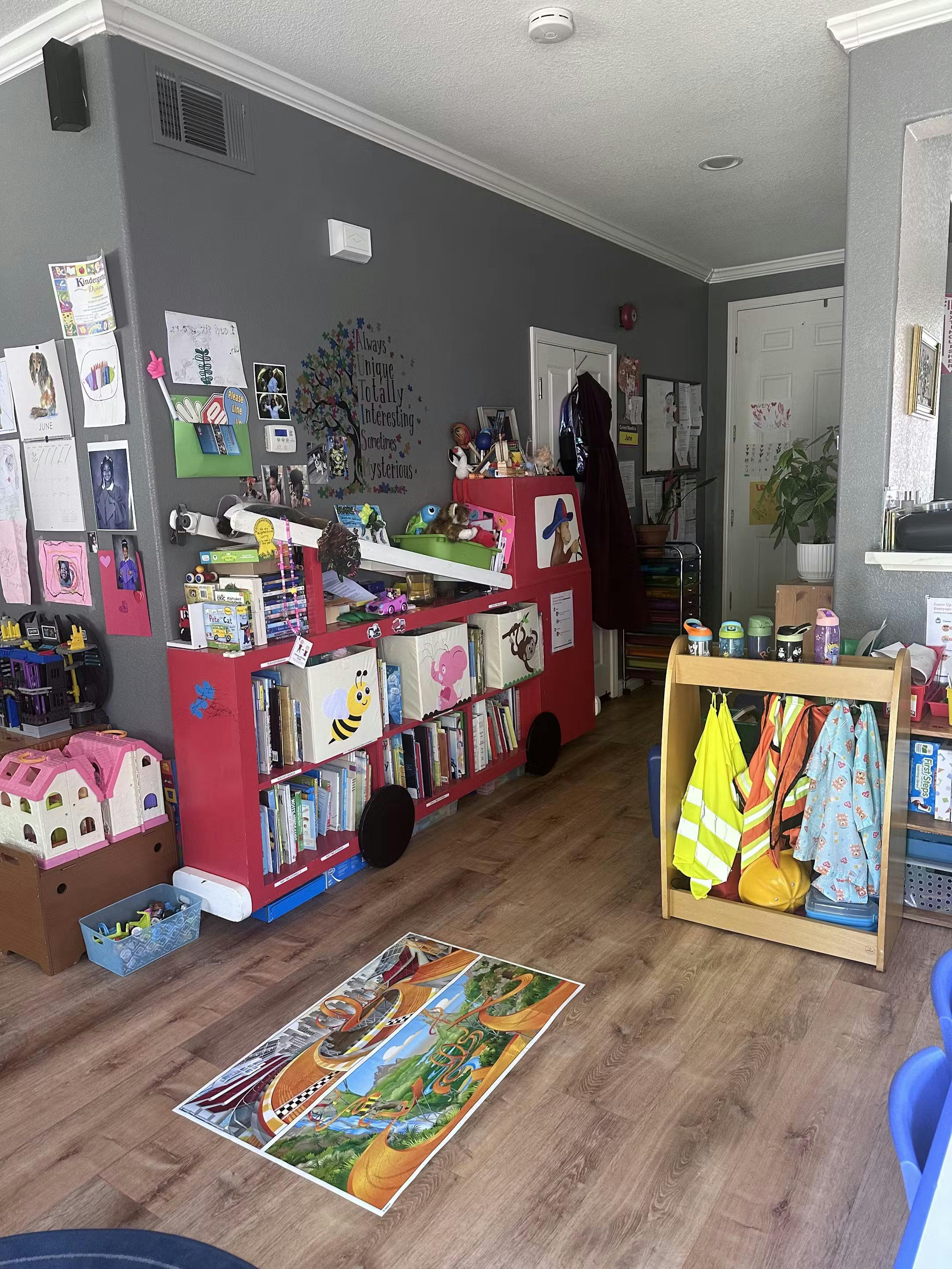 Children's play area with a red fire truck bookshelf and dress-up clothes