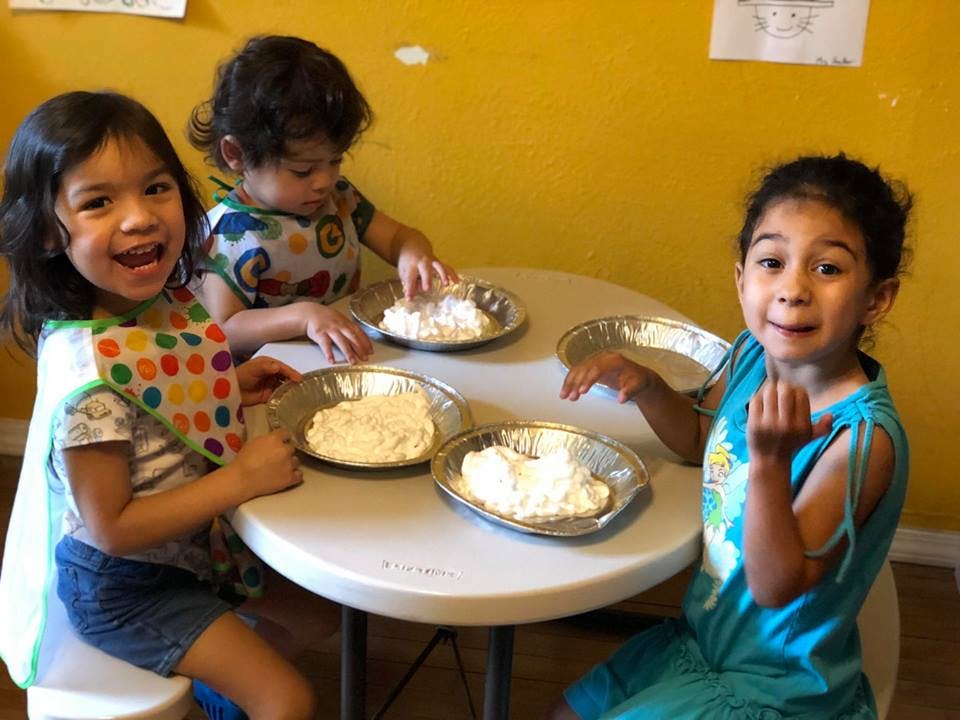 Three children at a table with pie tins of white material
