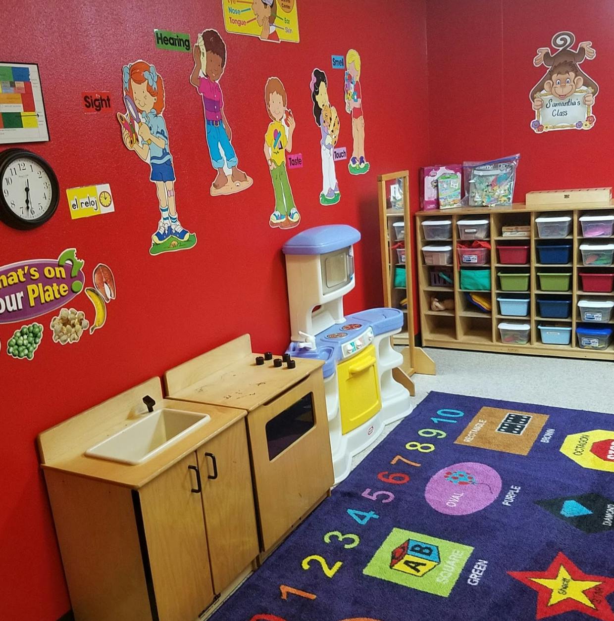 Playroom with red walls, toy kitchen, and a colorful rug