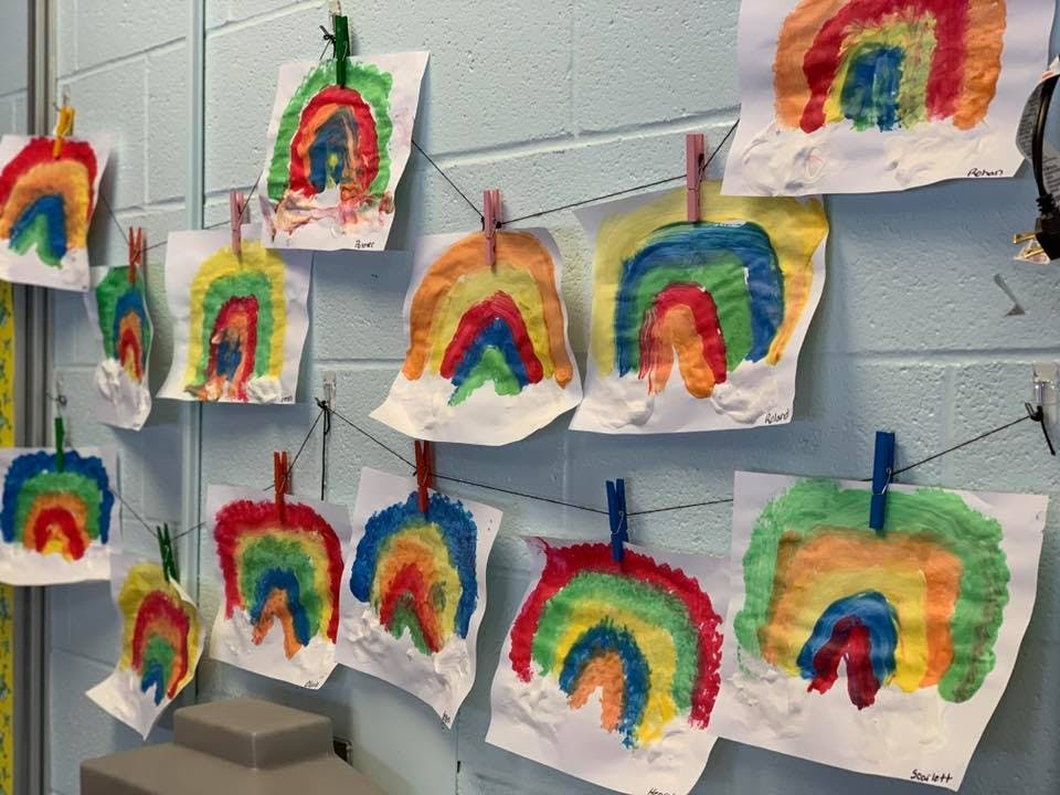Children's rainbow paintings hanging on a wall