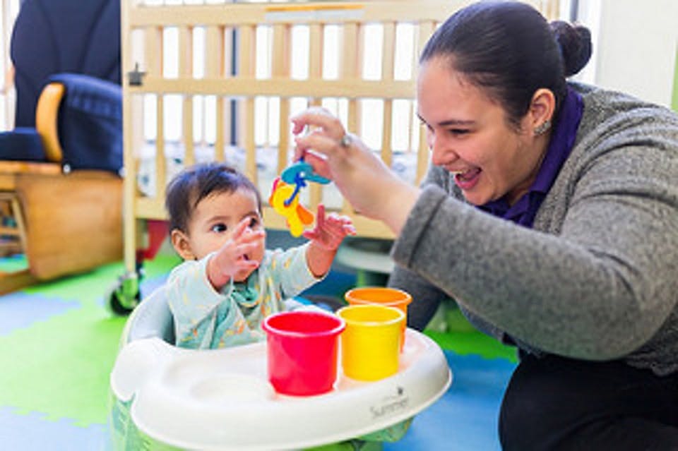 Adult holding a toy for a child in a high chair