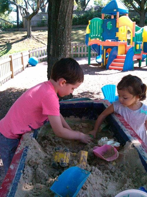 Two children playing in a sandbox