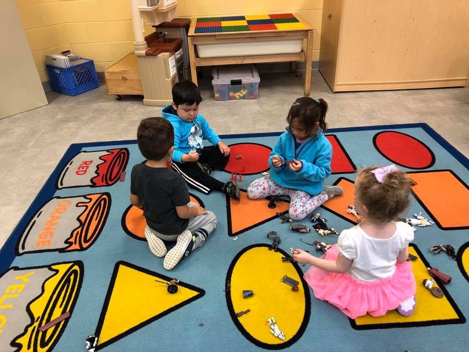 Four children playing with toys on a rug