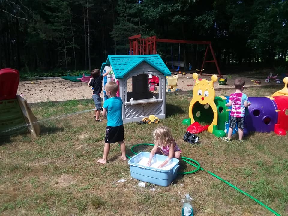 Children playing outdoors with a water bin and play structures