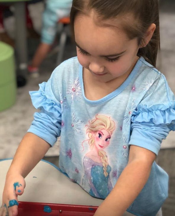 Child with blue paint on fingers