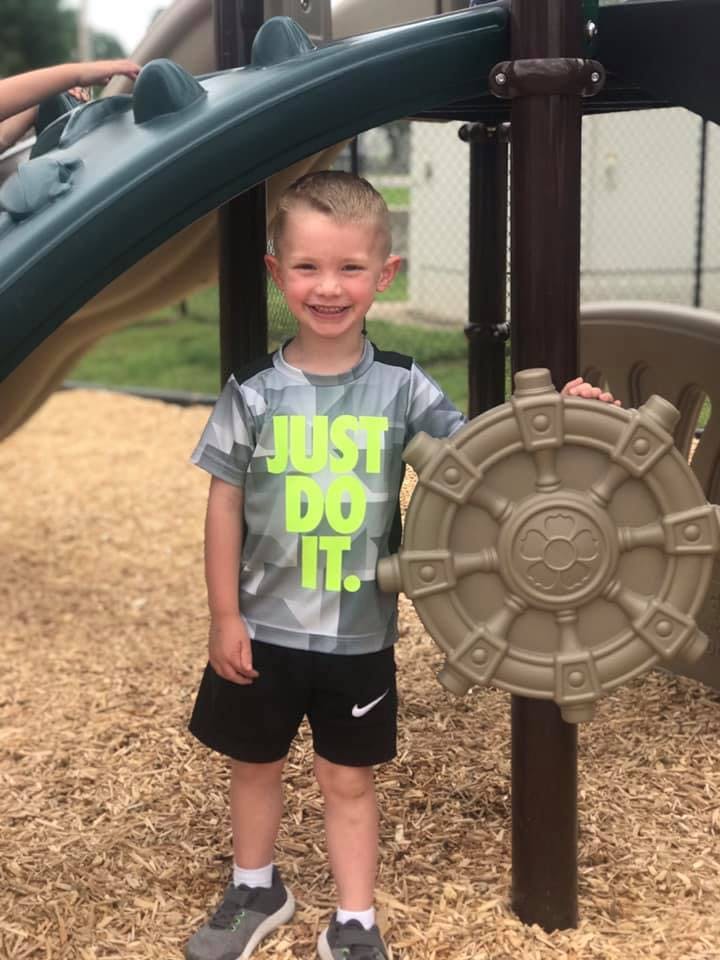 Child standing on wood chips next to playground equipment