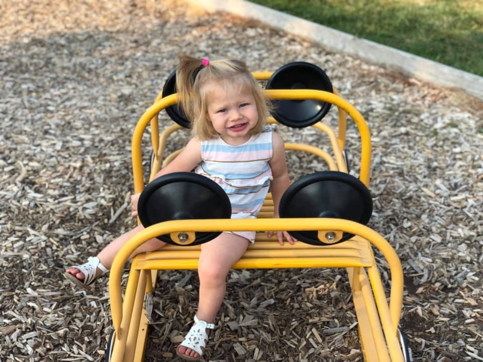 Child sitting on a yellow playground ride