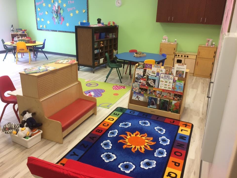 Children's classroom with small tables, chairs, and colorful rugs