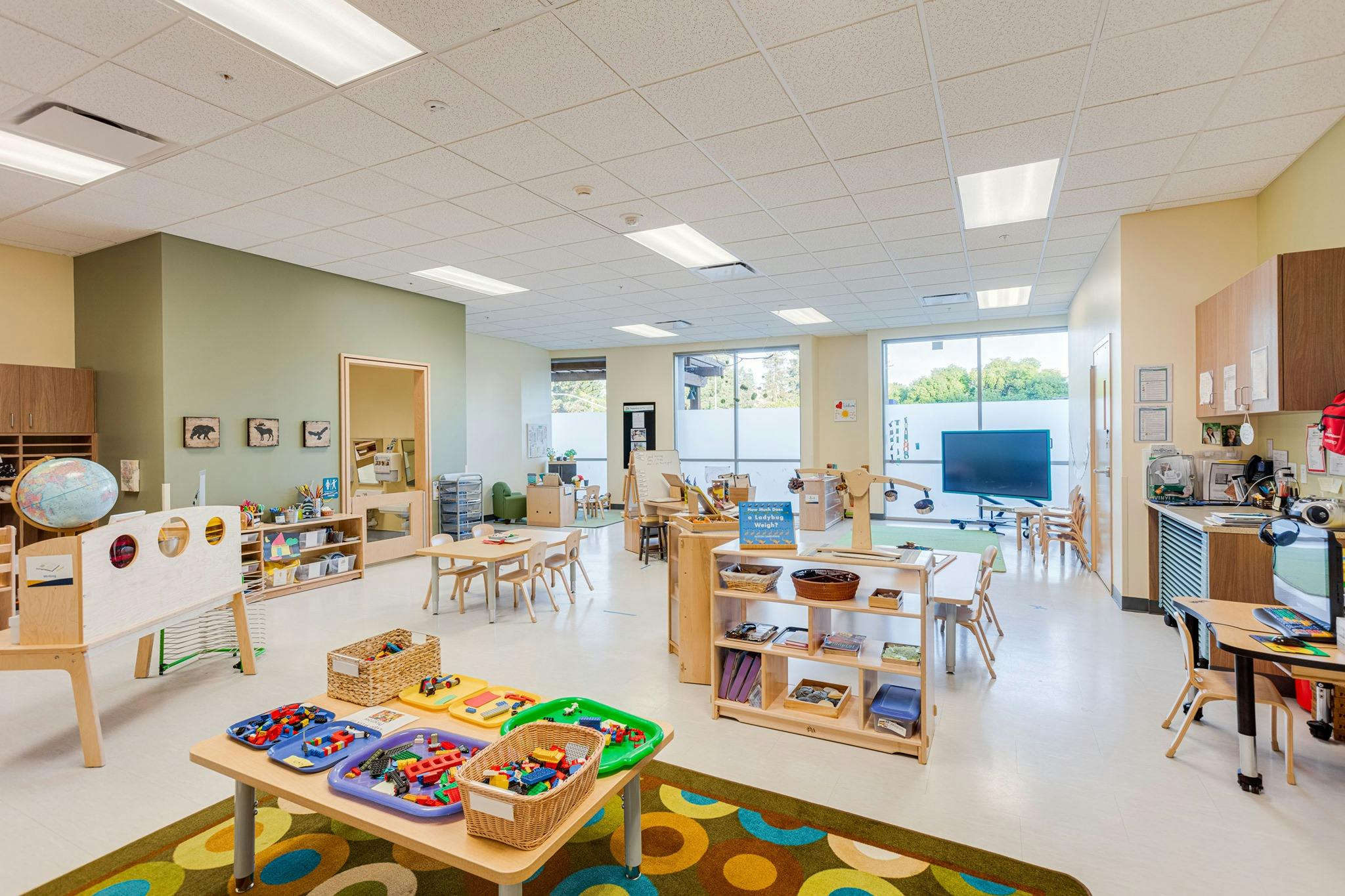 Classroom with tables, chairs, and shelves of learning materials