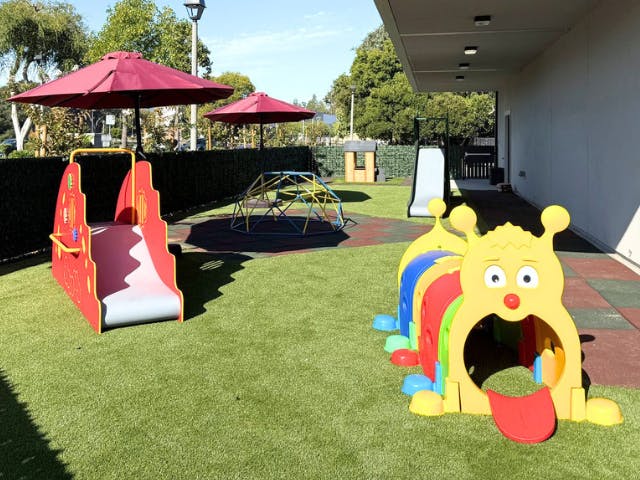 Playground equipment on artificial grass with umbrellas