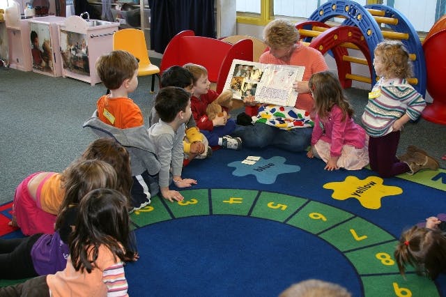 Adult reading a book to children in a classroom
