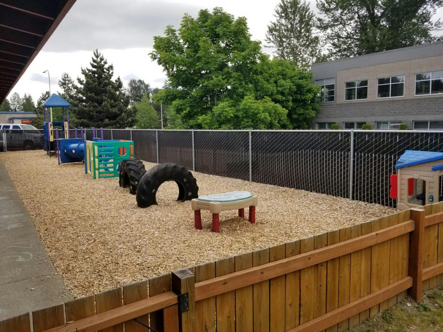 Outdoor playground with wood chips, play structures, and tire tunnels