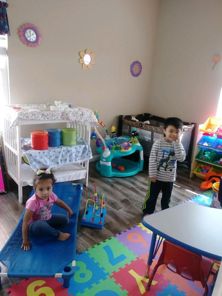Two children in a room with play equipment and a crib