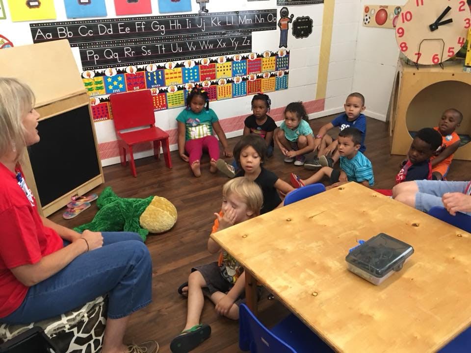 Person sitting on floor with children in a classroom