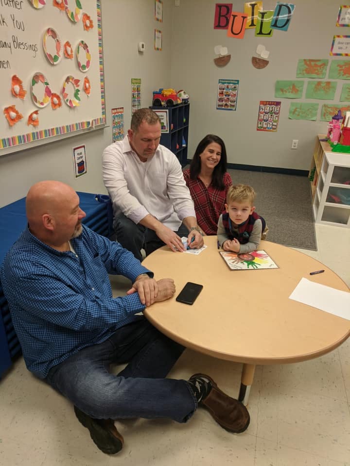 Two men, a woman, and a child sitting around a small table