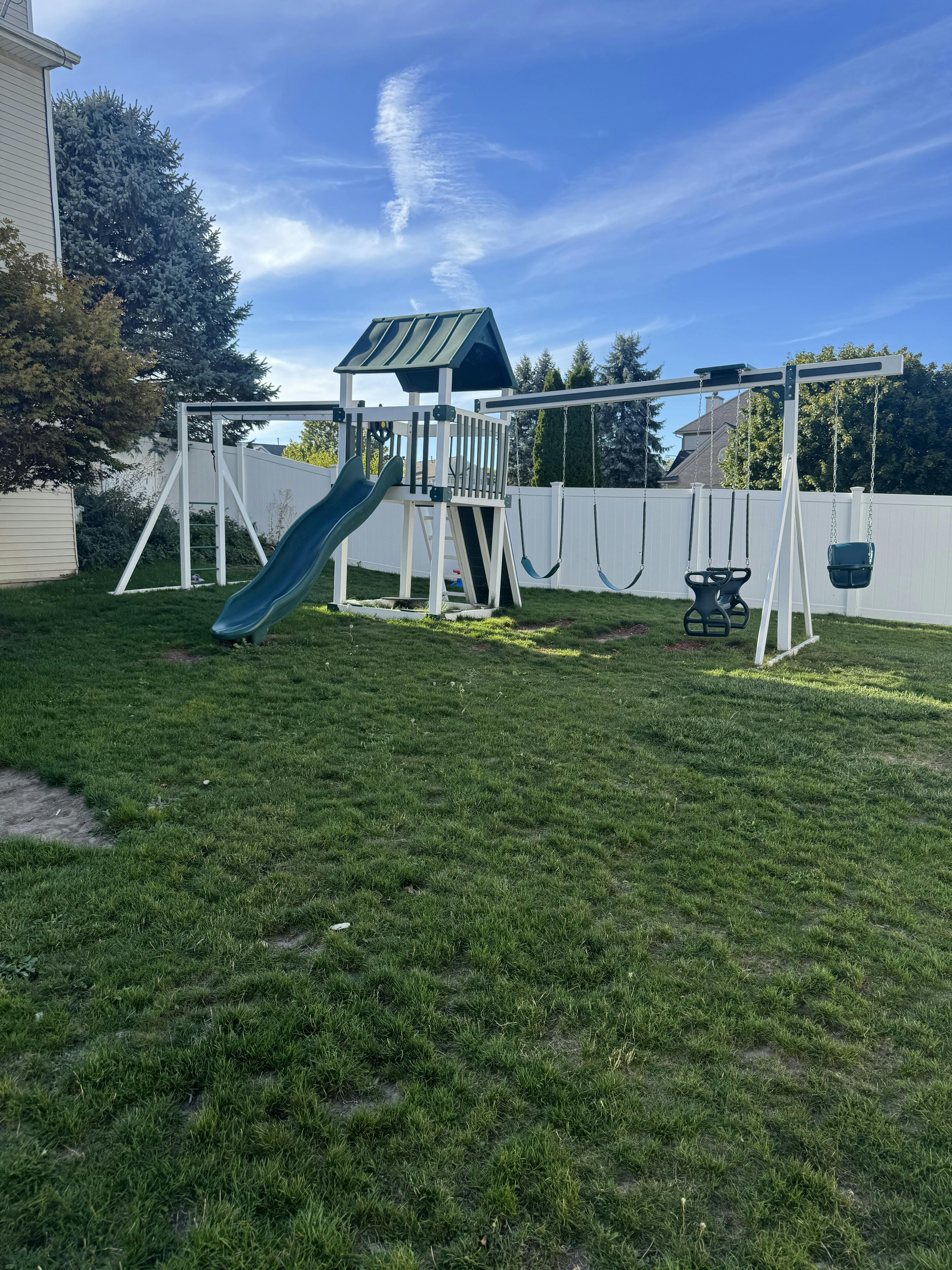 Playground set with a slide, swings, and a small playhouse