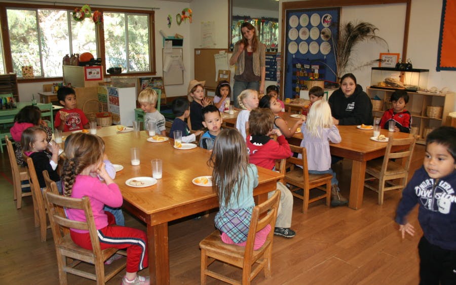 Children and adults seated at tables in a classroom