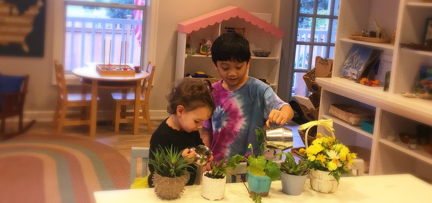 Two children tending to potted plants and flowers