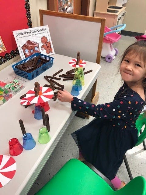 Child playing with building blocks and colorful cups at a table