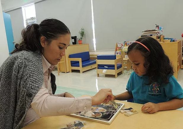 Adult and child working on a puzzle together in a classroom