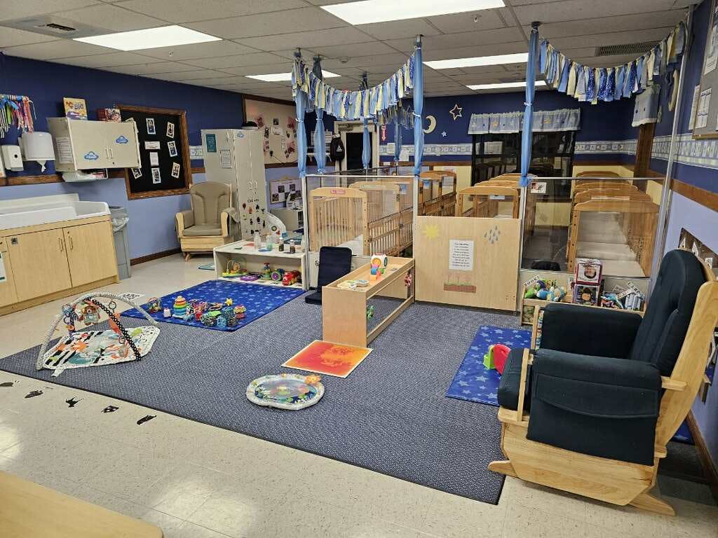 Cribs and play mats in a bright nursery room with blue walls