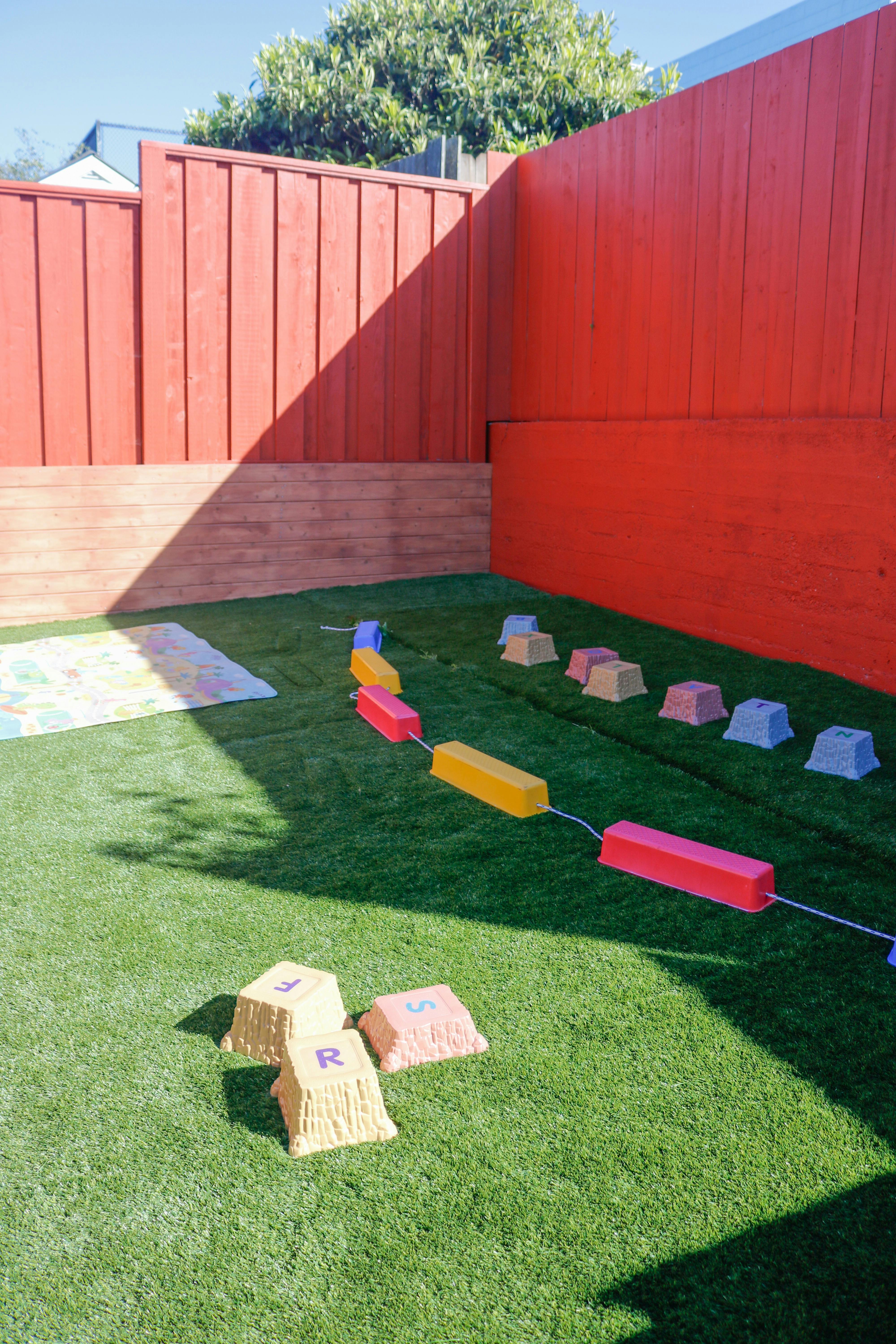 Play equipment on green turf in a fenced yard