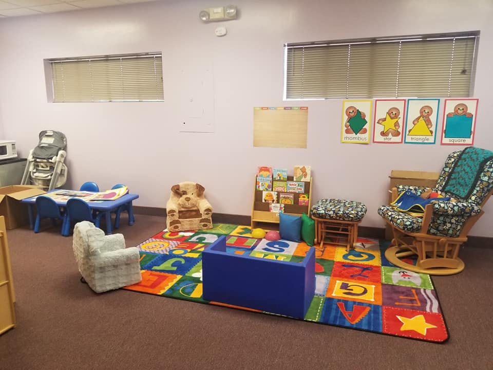 Children's play area with colorful rug, small table and chairs, and rocking chair
