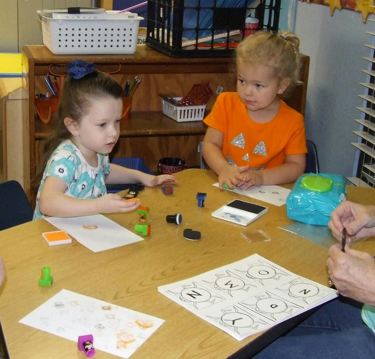 Two children at a table with papers and stamps