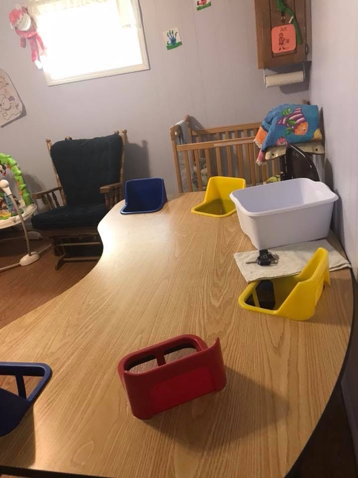 Table with several infant seats and a white tub in a room with a crib