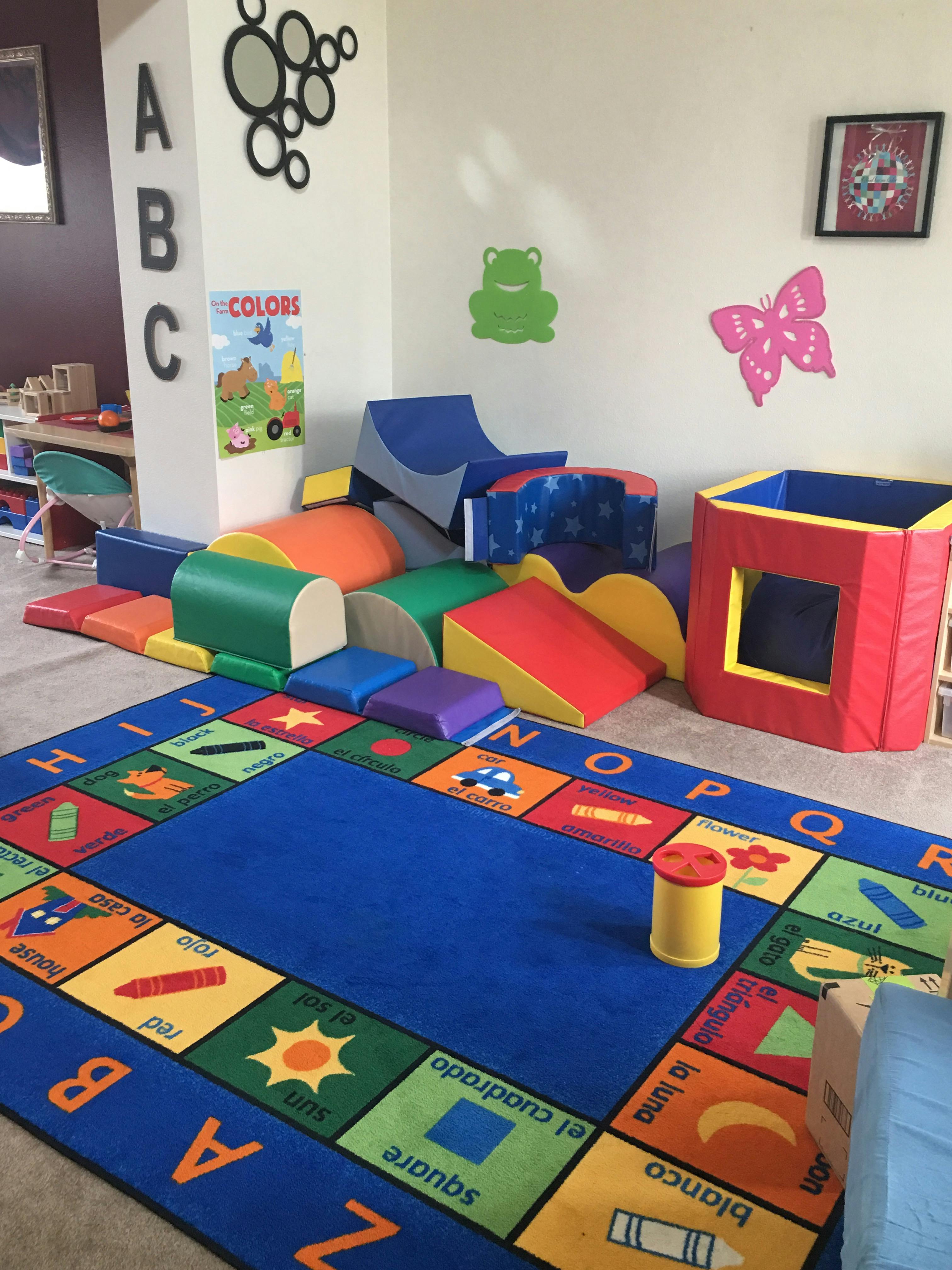 Playroom with soft play equipment and an alphabet rug