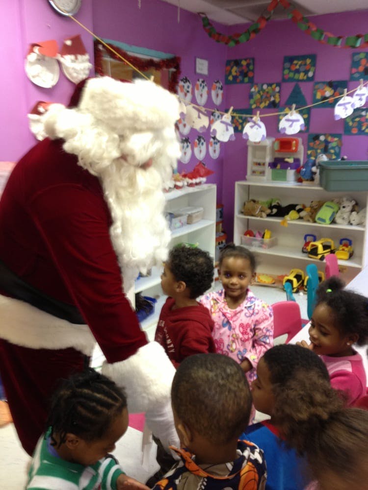 Person dressed as Santa Claus interacting with several children