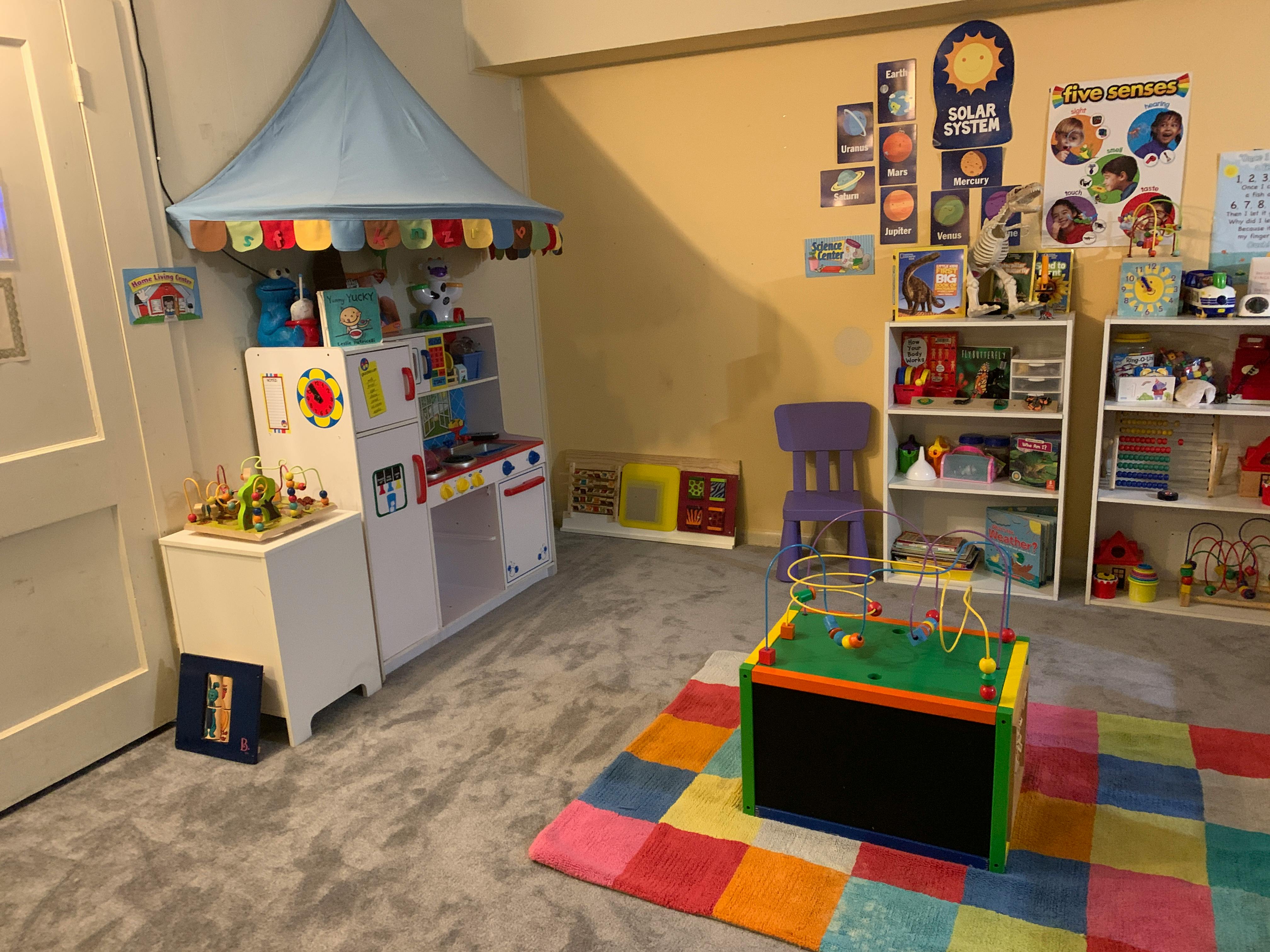 Playroom with toy kitchen, shelves of toys, and colorful rug