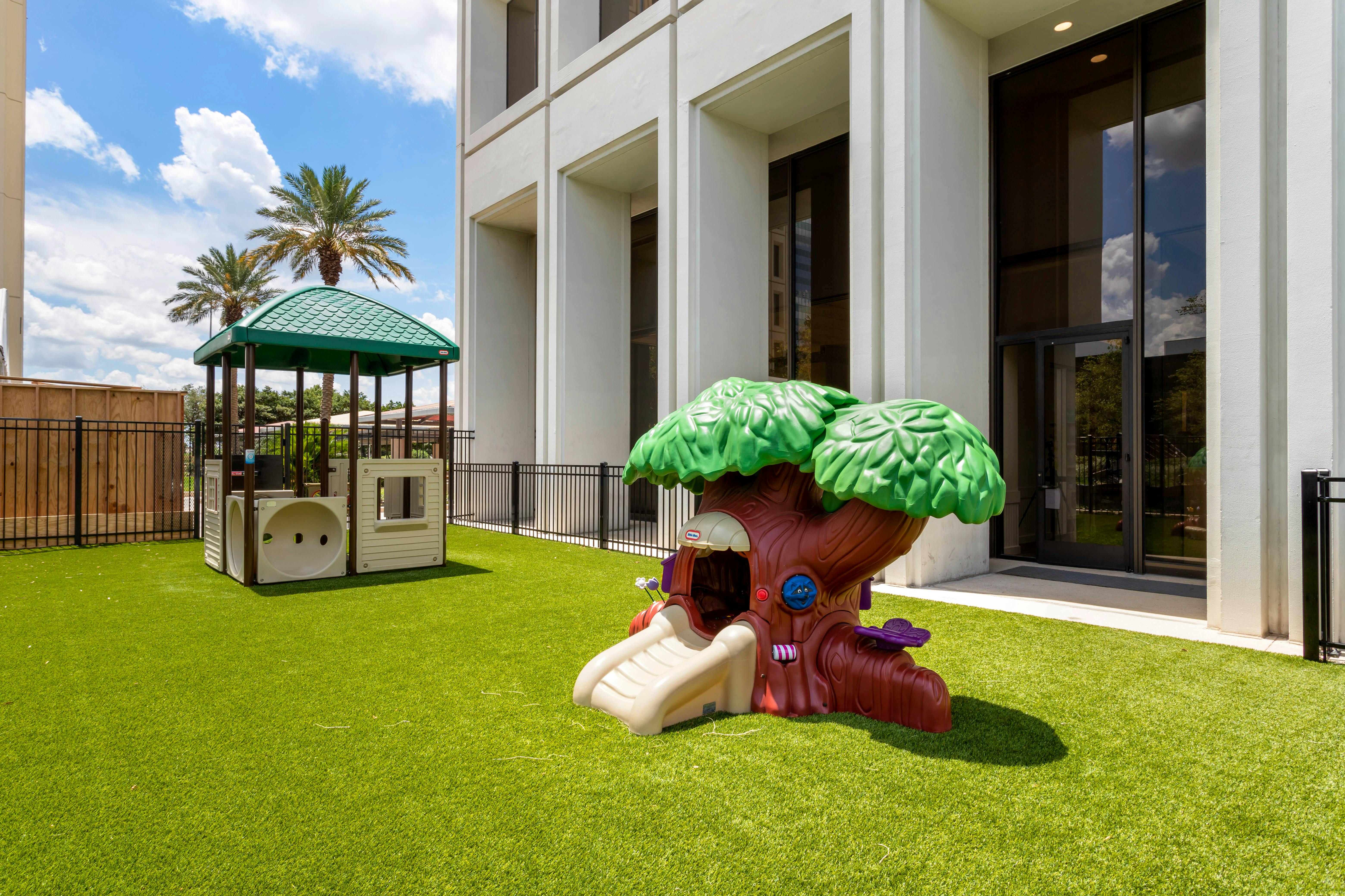 Outdoor playground with two small play structures on green artificial turf