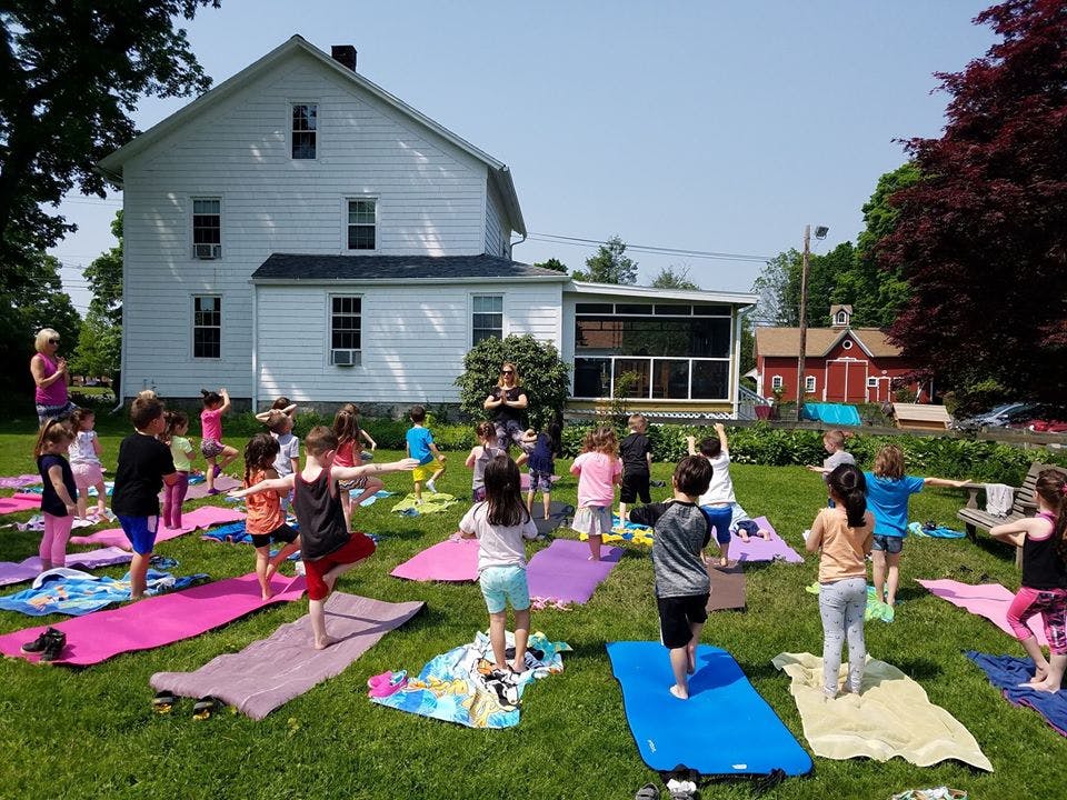 Children doing yoga outdoors on mats with an adult instructor