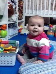 Child sitting on a mat next to a basket of toys