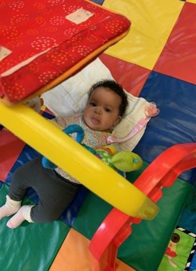 Child lying on a colorful playmat under a play gym