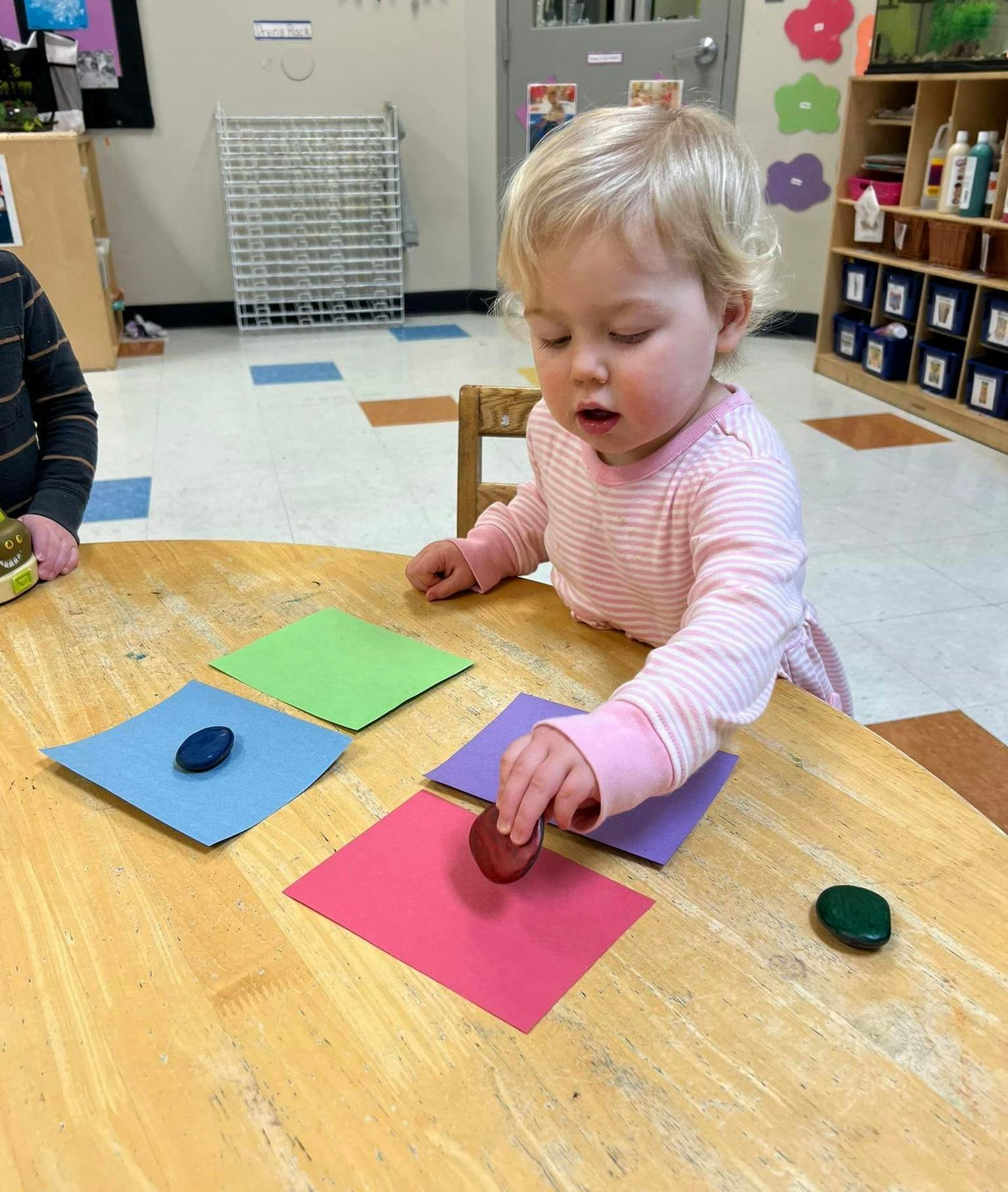 Child playing with crayons and colored paper on a table