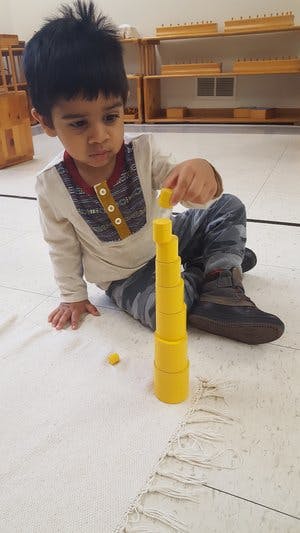 Child sitting on floor, stacking yellow blocks