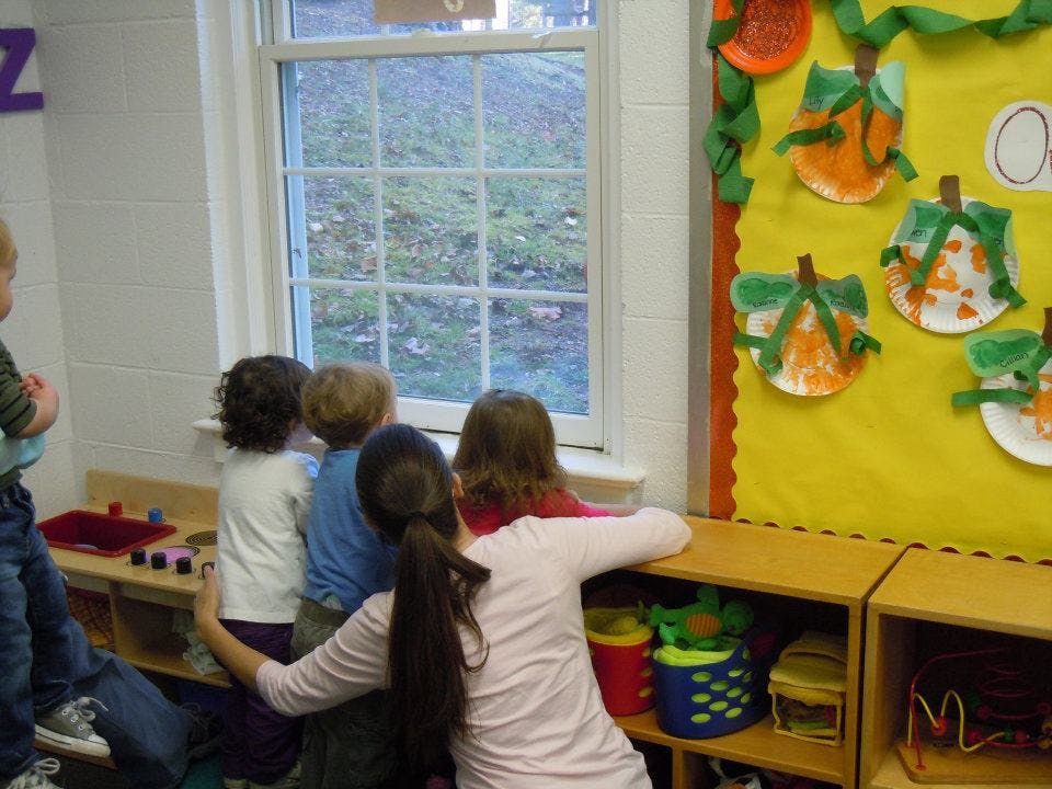 Children looking out a window in a classroom