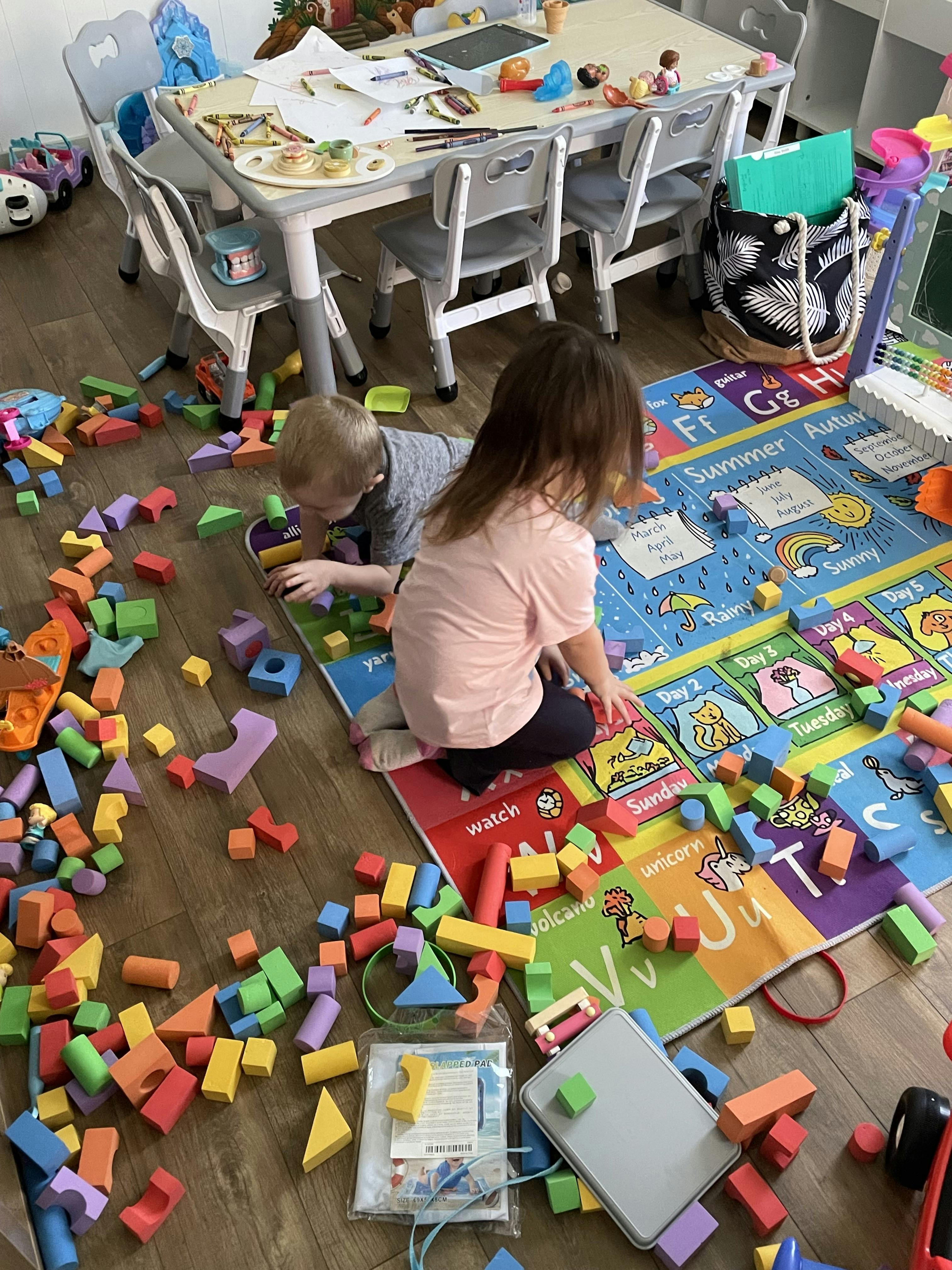 Two children playing with colorful building blocks on a mat