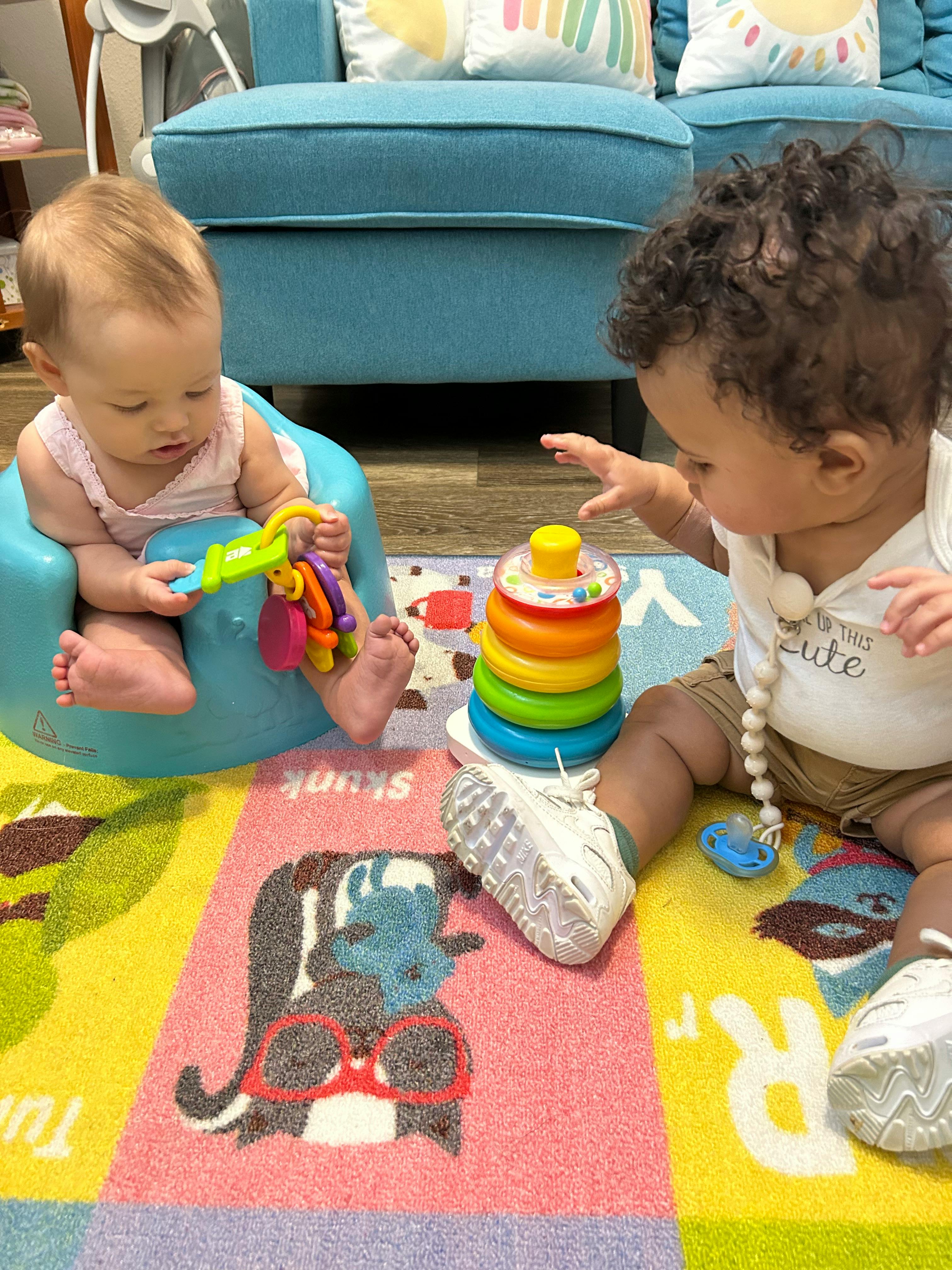Two children playing with toys on a colorful rug